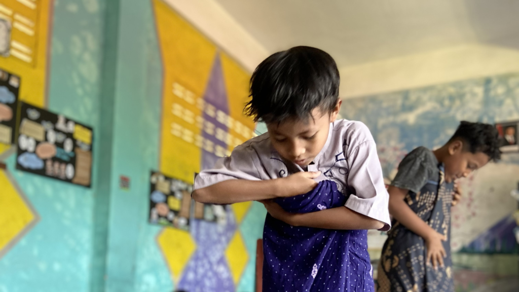 Siswa mempraktikkan bagaimana cara memakai sarung.